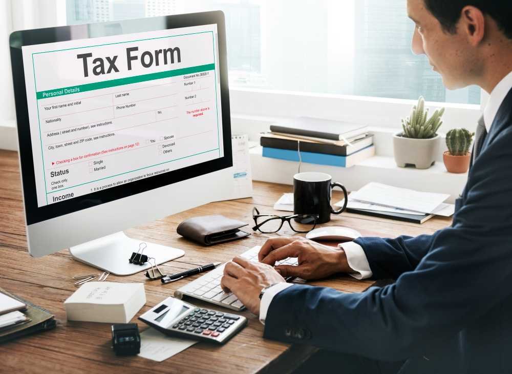 A person using a computer to complete an online tax form in an office environment.